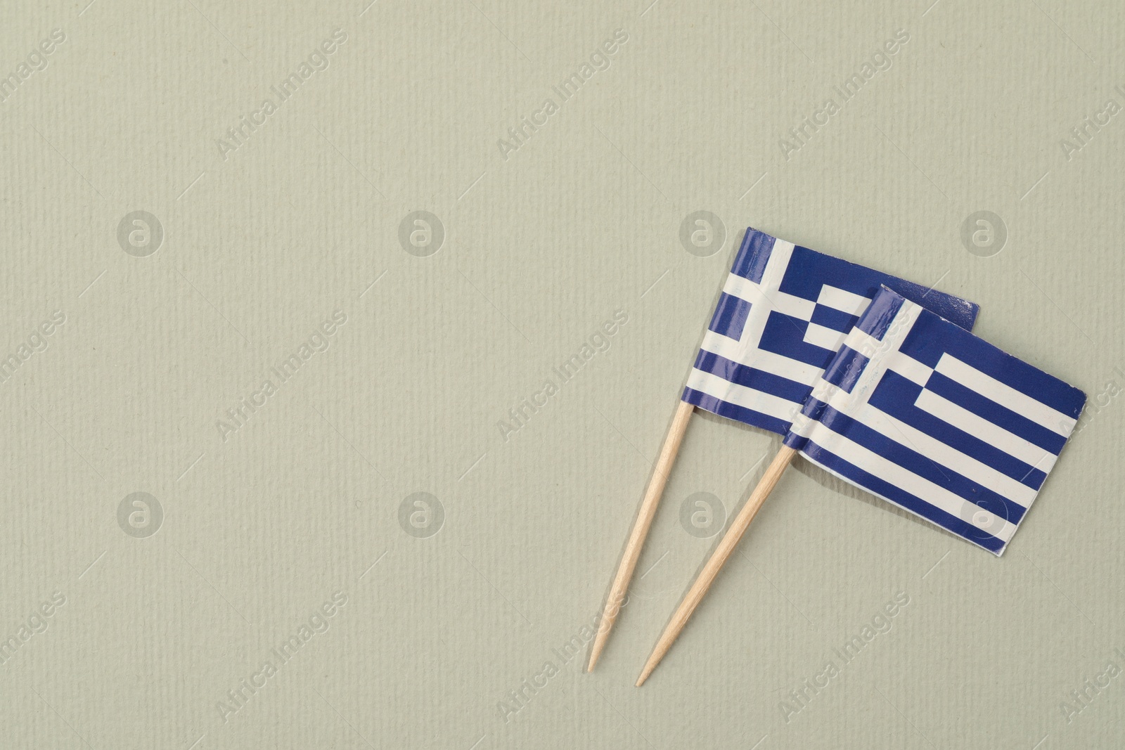 Photo of Small paper flags of Greece on light background, top view. Space for text