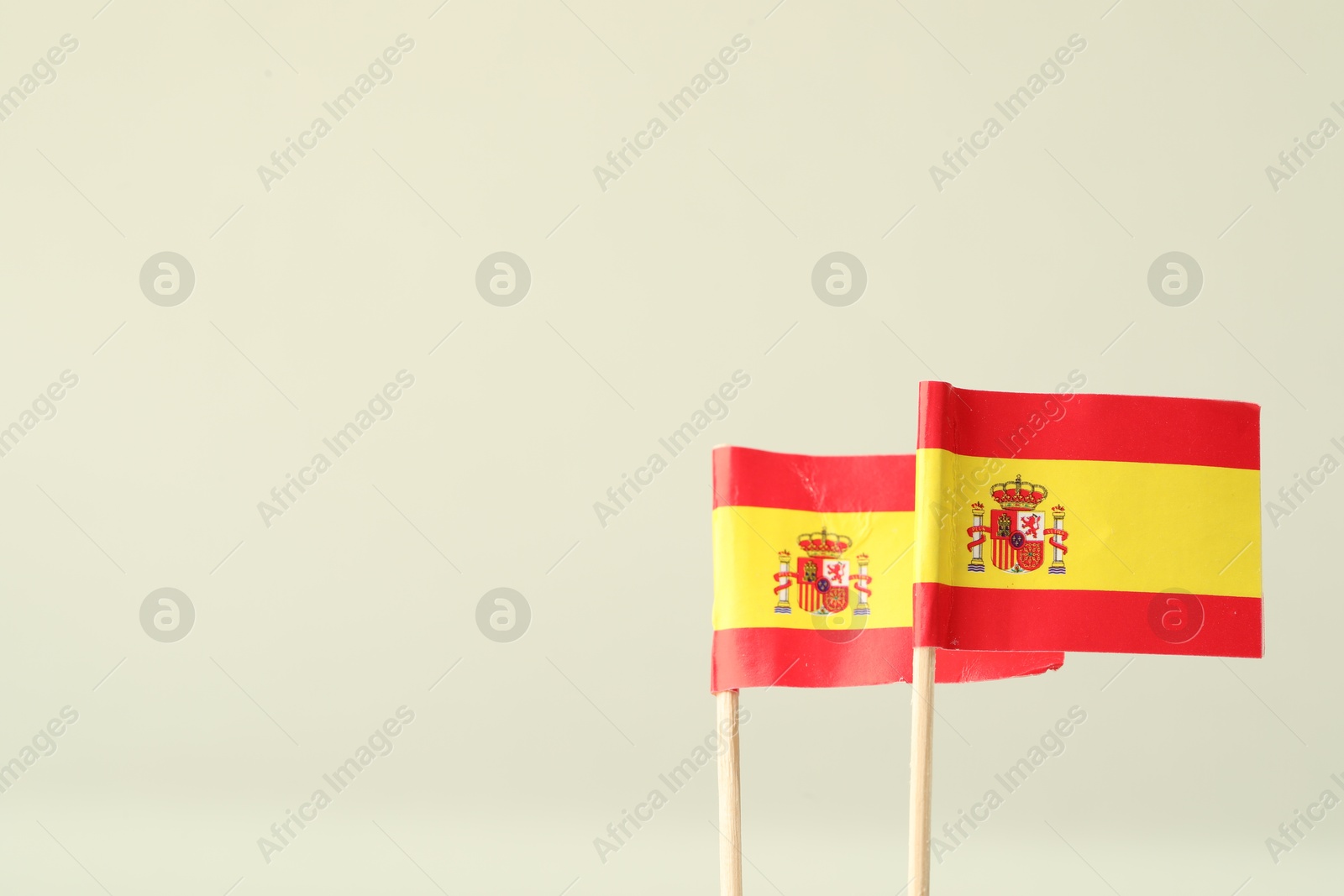 Photo of Small paper flags of Spain on light background, space for text