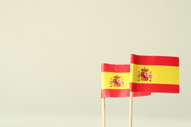 Photo of Small paper flags of Spain on light background, space for text