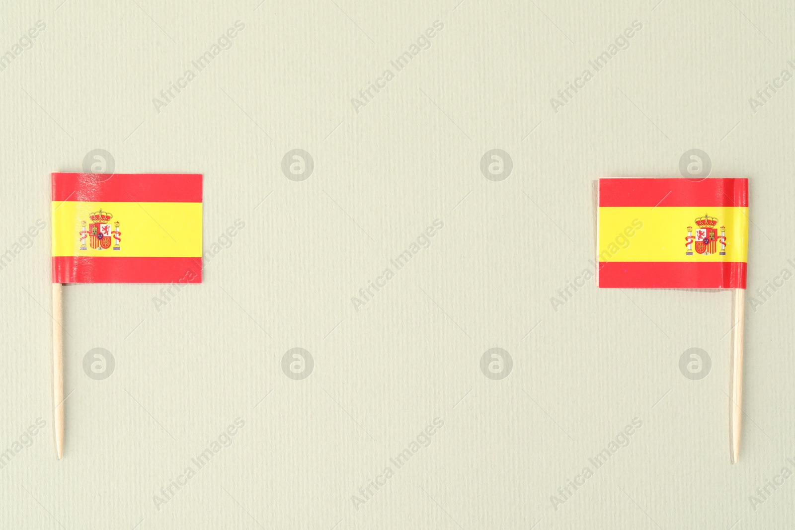 Photo of Small paper flags of Spain on light background, top view. Space for text