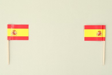 Photo of Small paper flags of Spain on light background, top view. Space for text