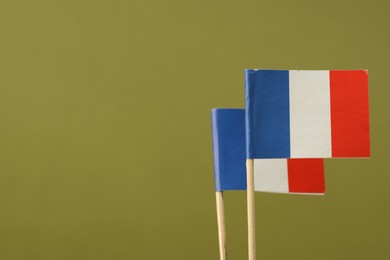 Small paper flags of France on olive background, space for text