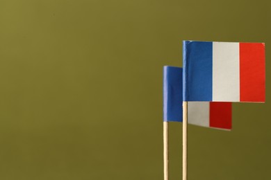 Small paper flags of France on olive background, space for text