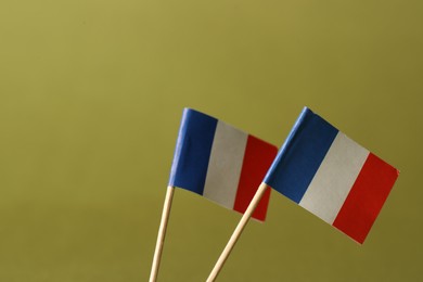 Small paper flags of France on olive background, space for text