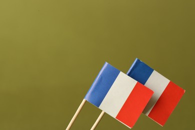 Small paper flags of France on olive background, space for text