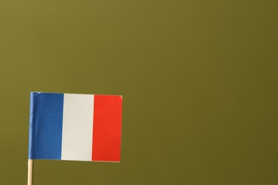 Small paper flag of France on olive background, space for text