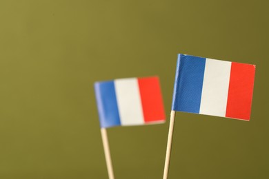 Small paper flags of France on olive background, space for text