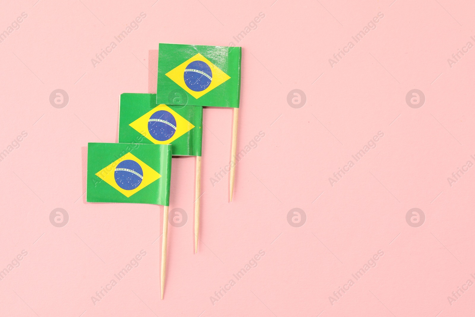 Photo of Small paper flags of Brazil on pink background, top view. Space for text