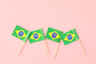 Photo of Small paper flags of Brazil on pink background, top view