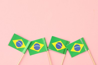 Small paper flags of Brazil on pink background, top view. Space for text