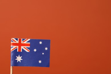 Small paper flag of Australia on orange background, space for text