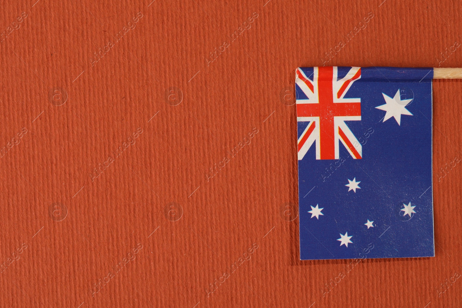 Photo of Small paper flag of Australia on orange background, top view. Space for text