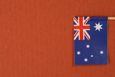 Photo of Small paper flag of Australia on orange background, top view. Space for text