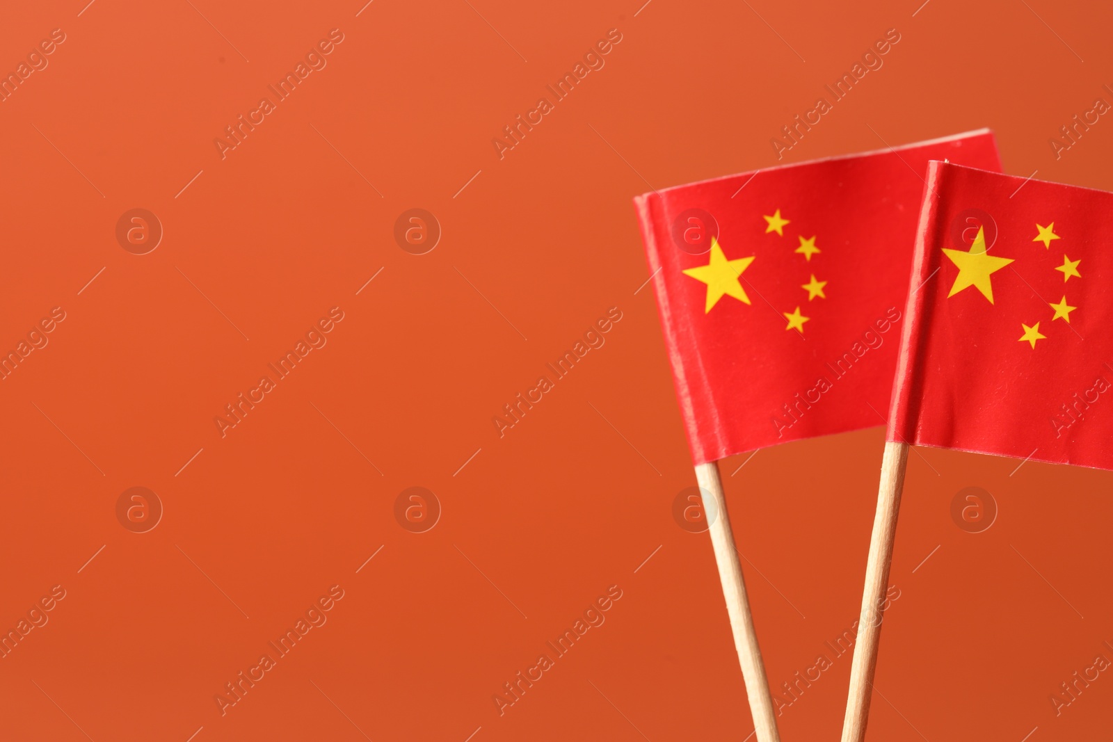 Photo of Small paper flags of China on orange background, space for text