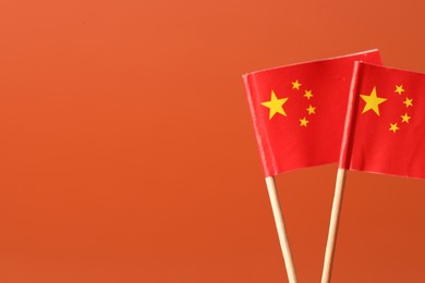 Small paper flags of China on orange background, space for text