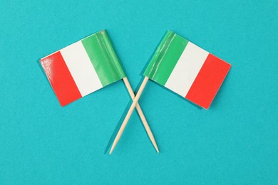 Photo of Small paper flags of Italy on light blue background, top view