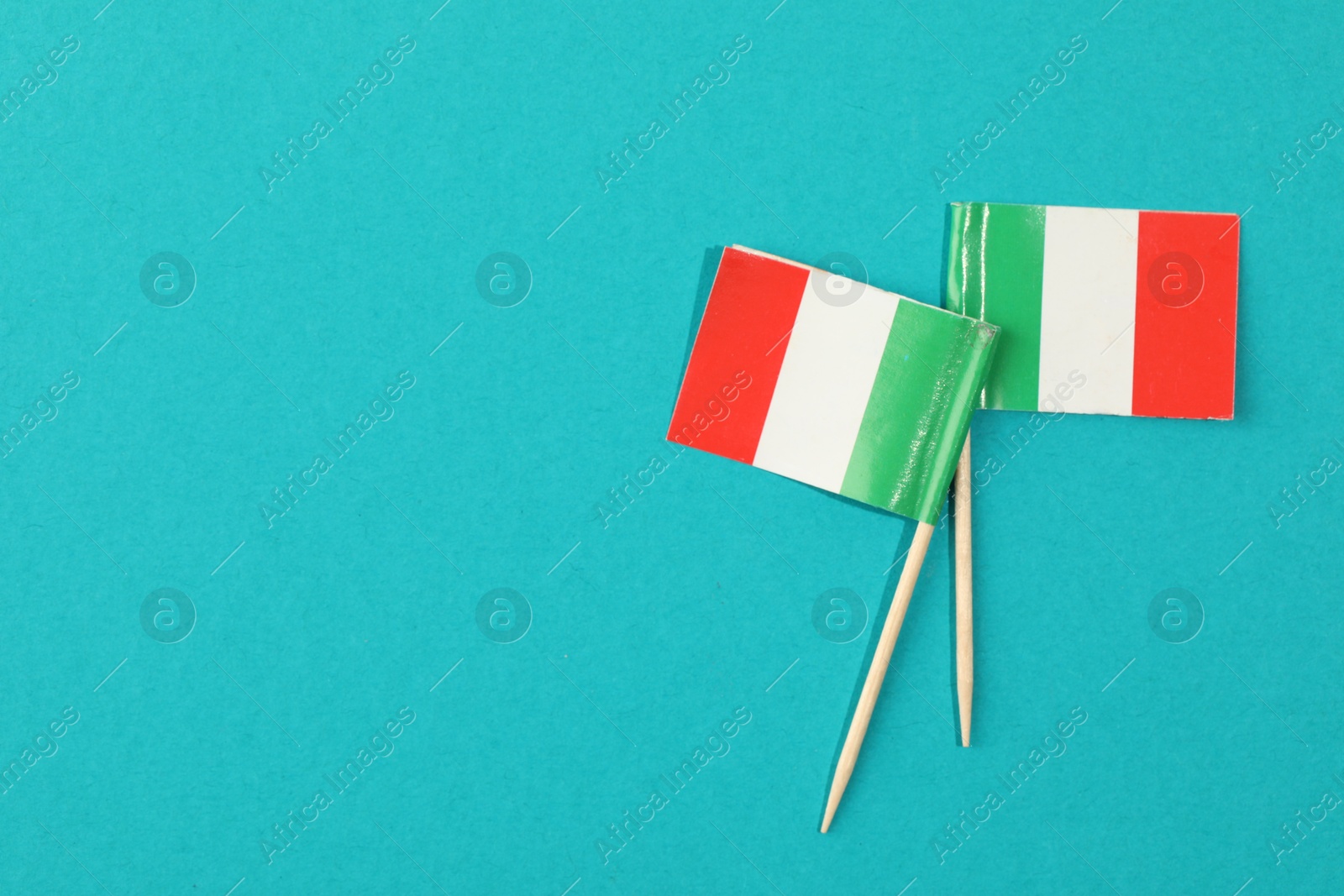 Photo of Small paper flags of Italy on light blue background, top view. Space for text