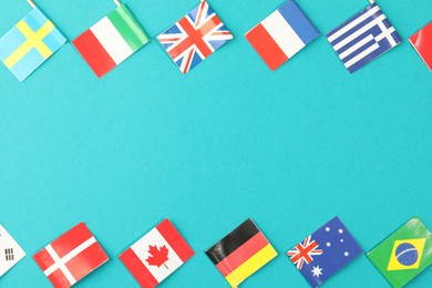 Small paper flags of different countries on light blue background, flat lay. Space for text