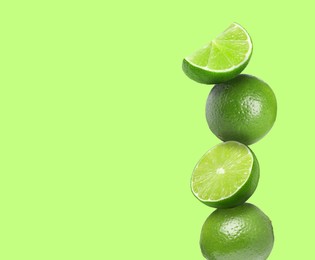 Image of Stacked fresh limes on light green background, space for text