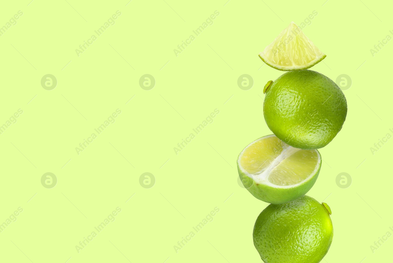 Image of Stacked fresh limes on light green background, space for text