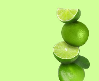 Image of Stacked fresh limes on light green background, space for text