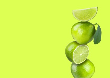 Image of Stacked fresh limes on yellowish green background, space for text