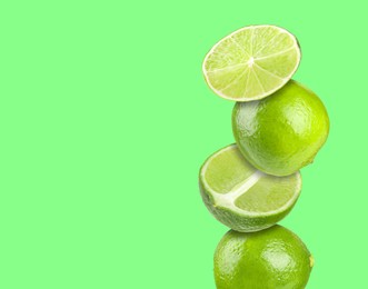 Image of Stacked fresh limes on green background, space for text