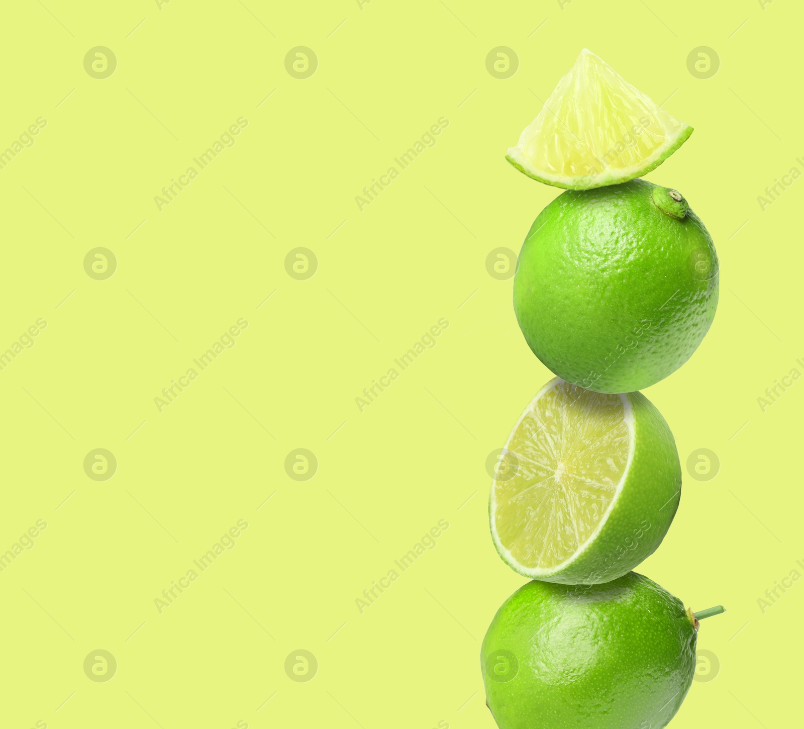 Image of Stacked fresh limes on yellowish green background, space for text