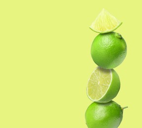 Image of Stacked fresh limes on yellowish green background, space for text