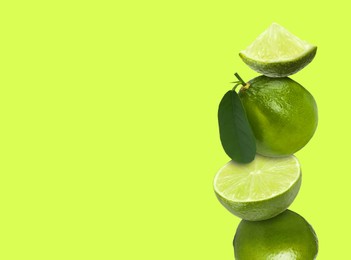 Image of Stacked fresh limes on yellowish green background, space for text