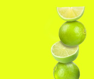 Image of Stacked fresh limes on yellowish green background, space for text