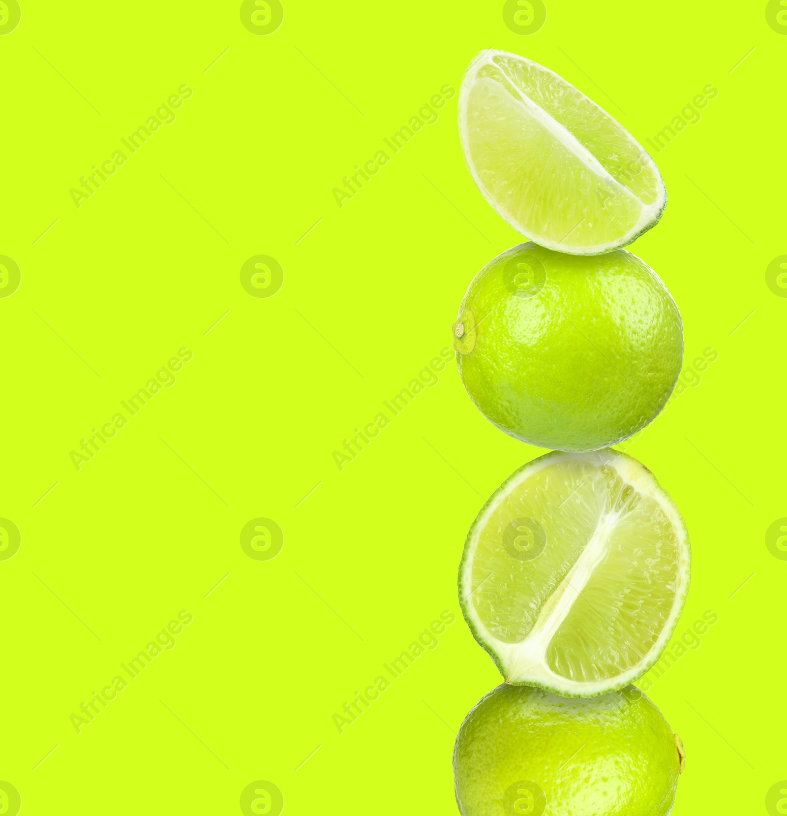 Image of Stacked fresh limes on yellowish green background, space for text