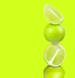 Image of Stacked fresh limes on yellowish green background, space for text