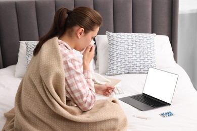 Sick woman having online consultation with doctor via laptop at home