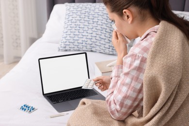 Sick woman with pills having online consultation with doctor via laptop at home