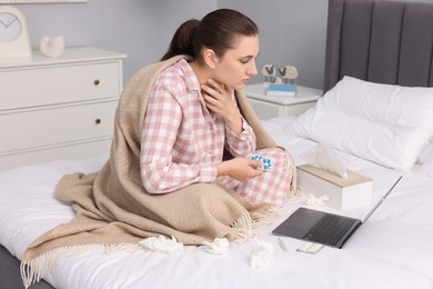 Sick woman with pills having online consultation with doctor via laptop at home