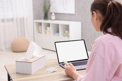 Sick woman with nasal spray having online consultation with doctor via laptop at wooden table indoors