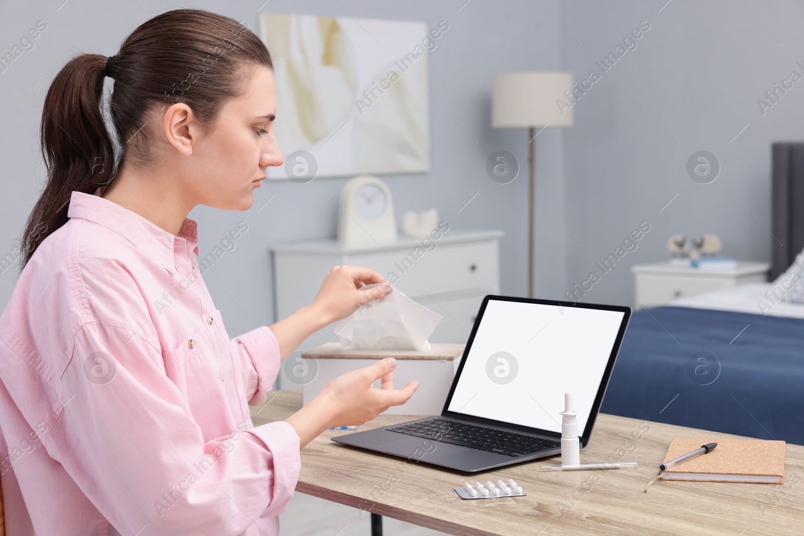 Photo of Sick woman having online consultation with doctor via laptop at wooden table indoors