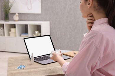 Photo of Sick woman having online consultation with doctor via laptop at wooden table indoors