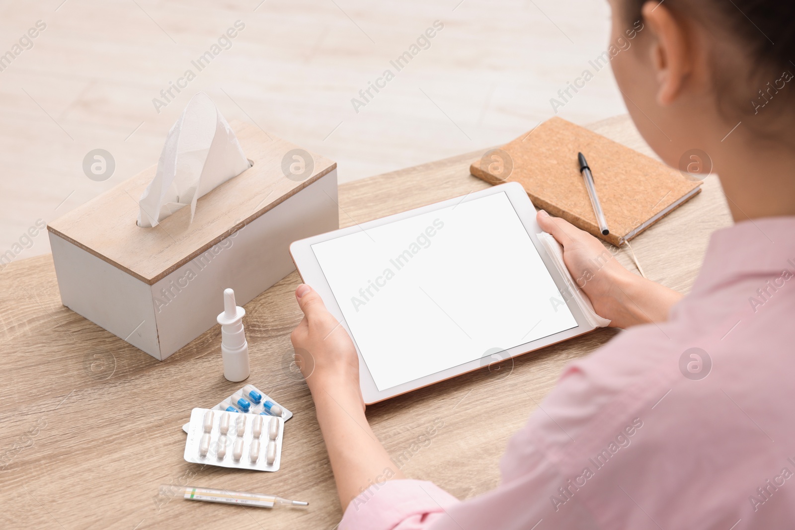 Photo of Sick woman having online consultation with doctor via tablet at wooden table, closeup