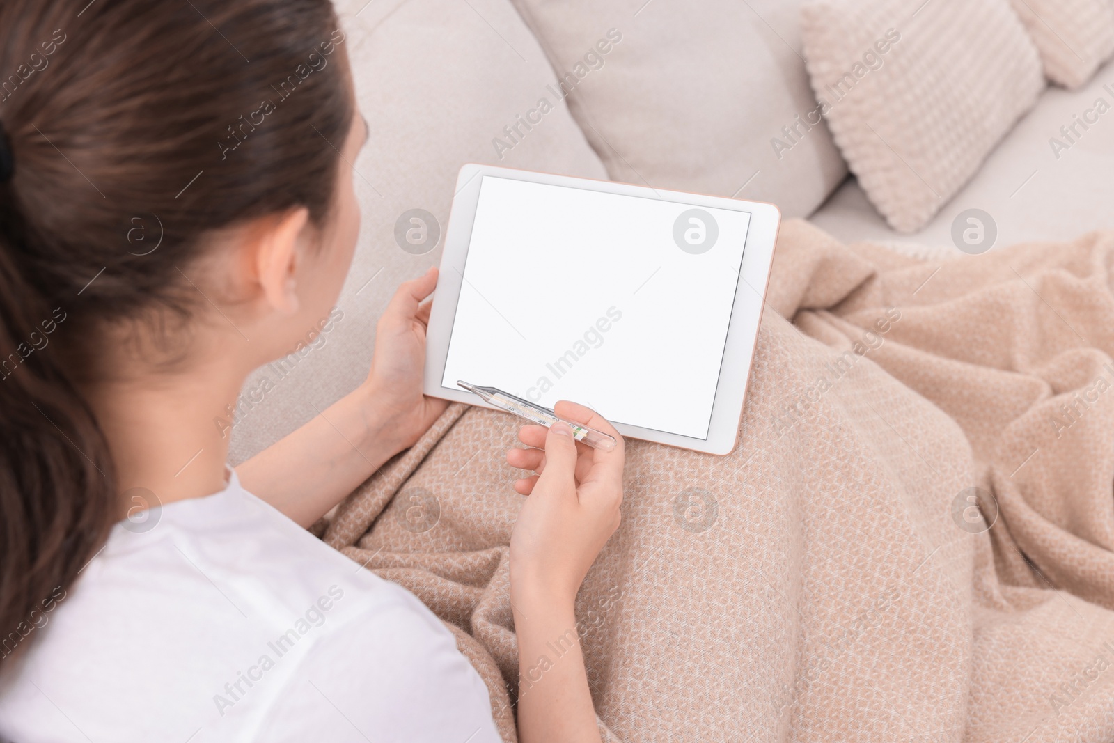 Photo of Sick woman with thermometer having online consultation with doctor via tablet at home