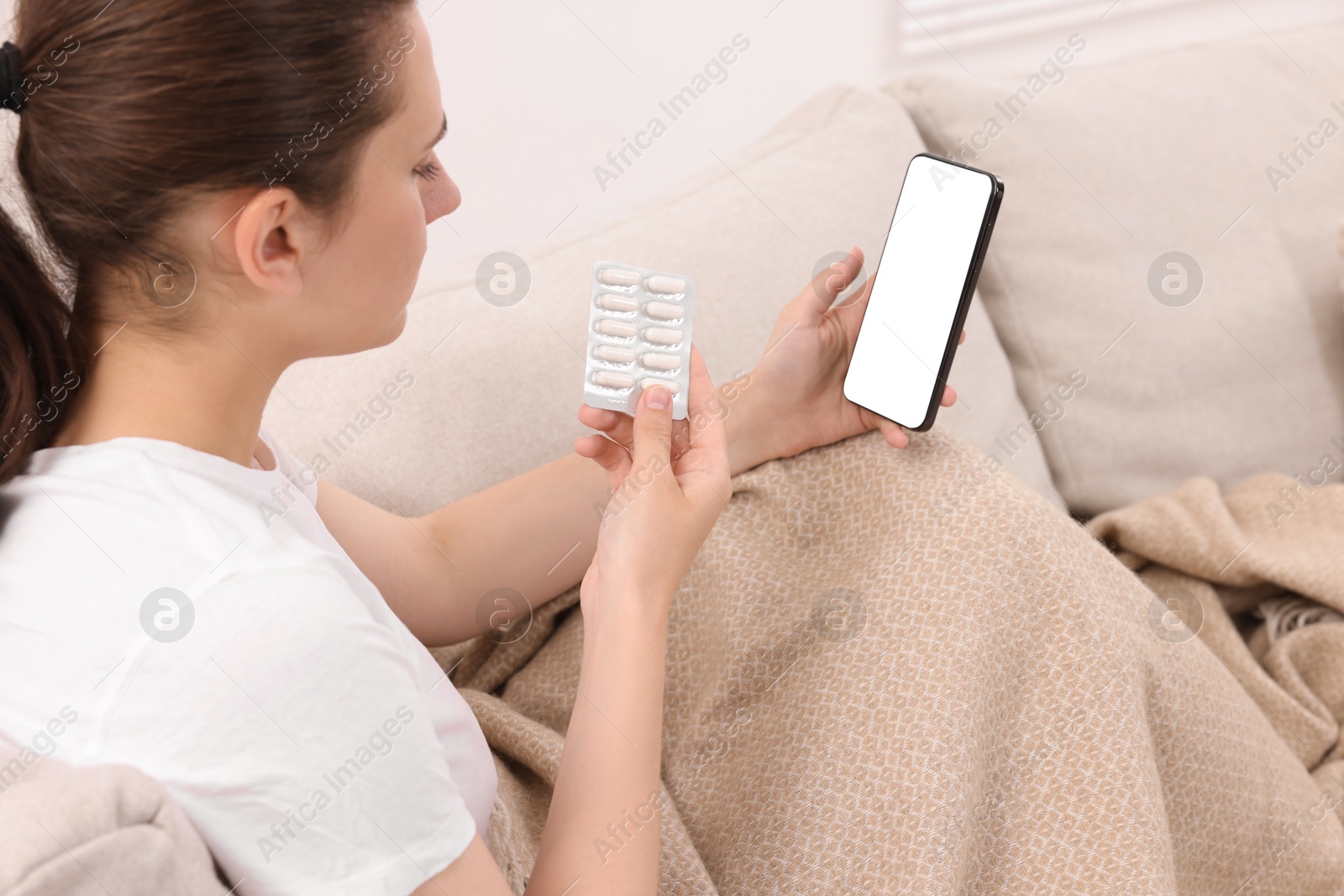 Photo of Sick woman with pills having online consultation with doctor via smartphone at home