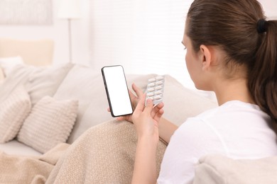 Photo of Sick woman with pills having online consultation with doctor via smartphone at home