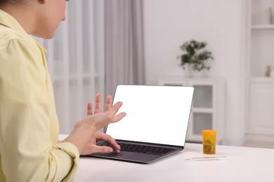 Sick woman having online consultation with doctor via laptop at white table indoors, closeup