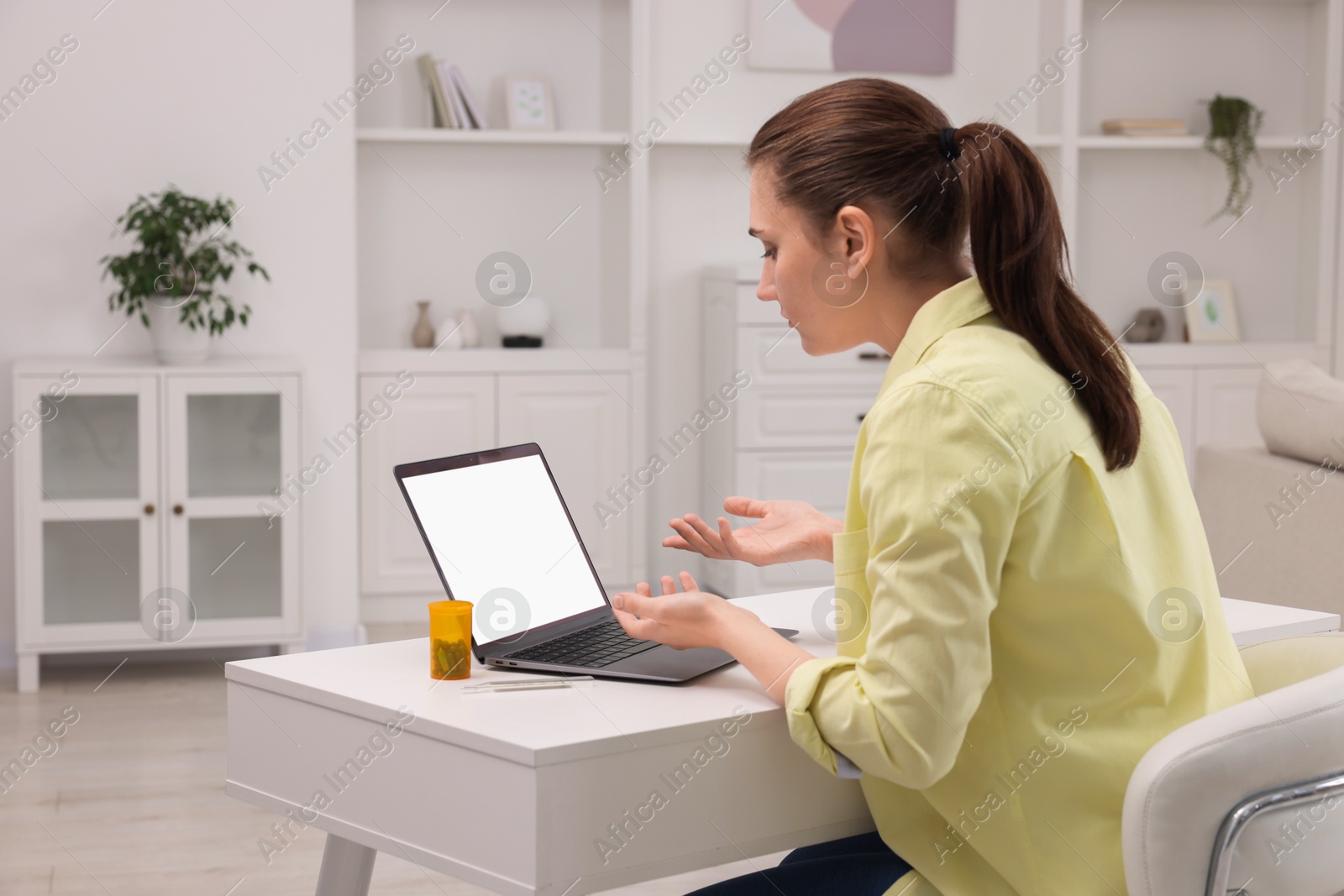 Photo of Sick woman having online consultation with doctor via laptop at white table indoors