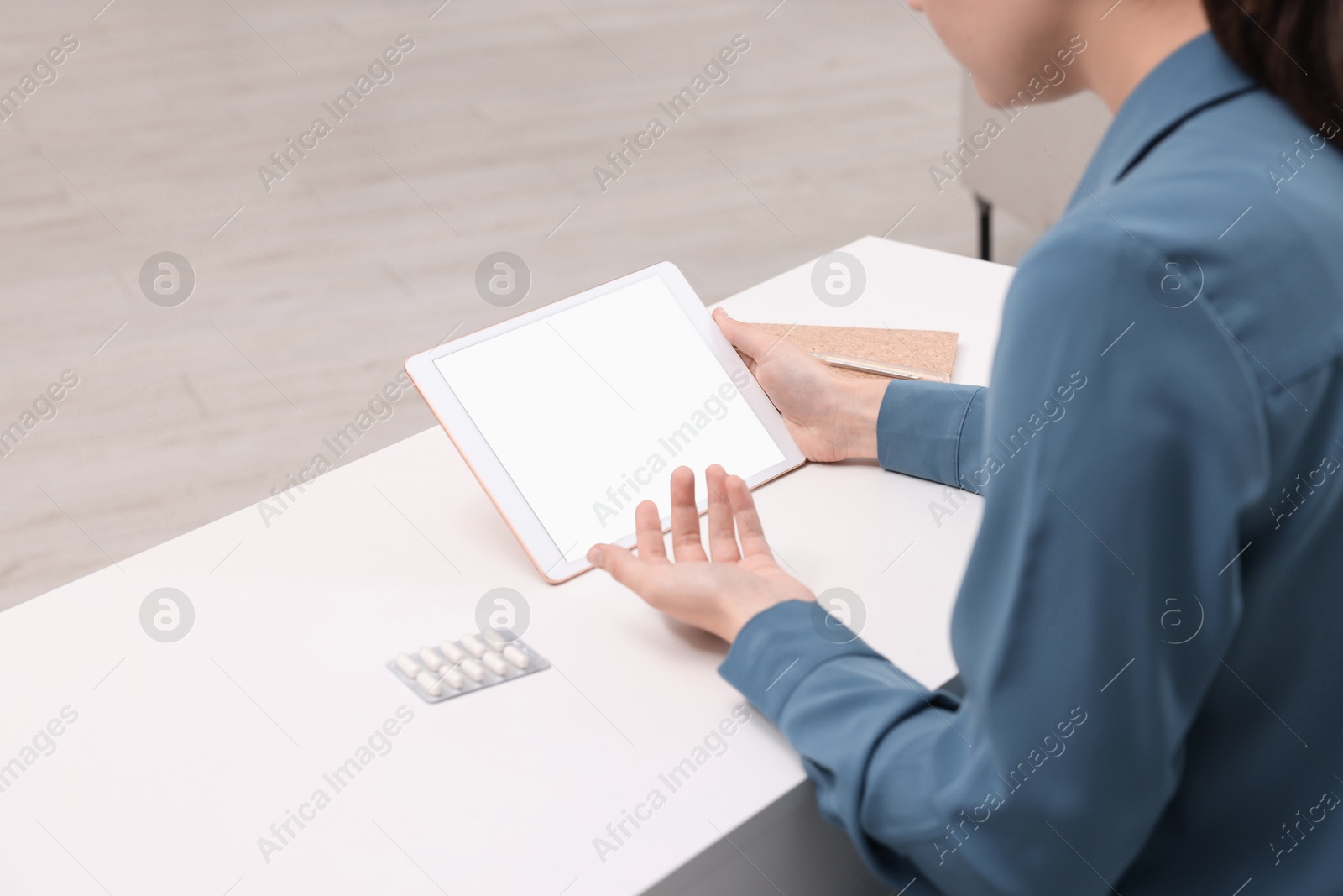 Photo of Sick woman having online consultation with doctor via tablet at white table indoors, closeup