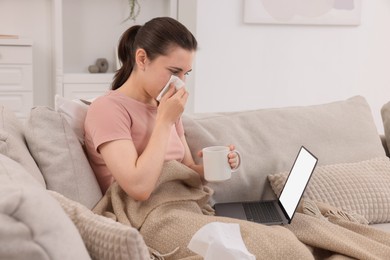 Sick woman having online consultation with doctor via laptop at home