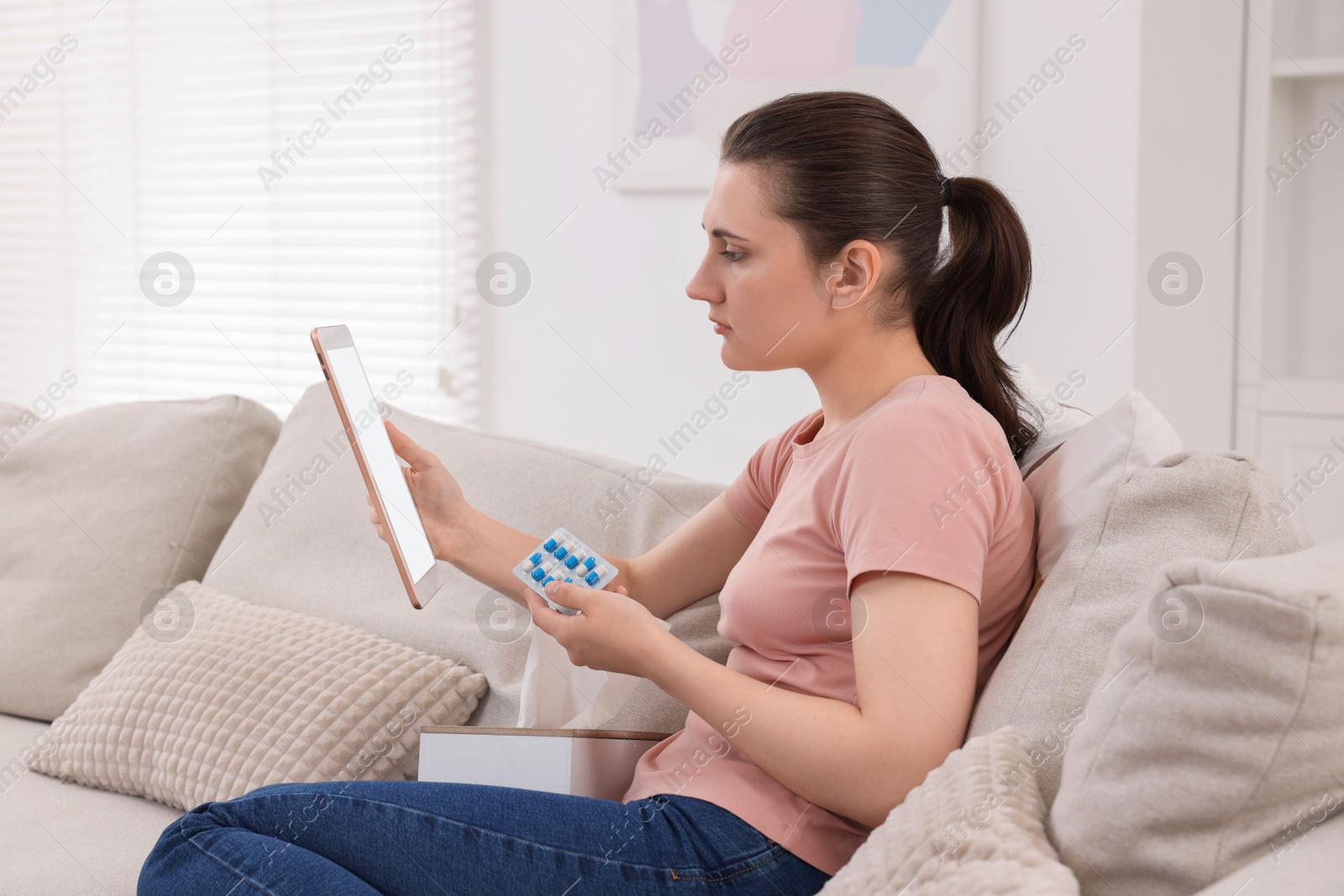 Photo of Sick woman with pills having online consultation with doctor via tablet at home