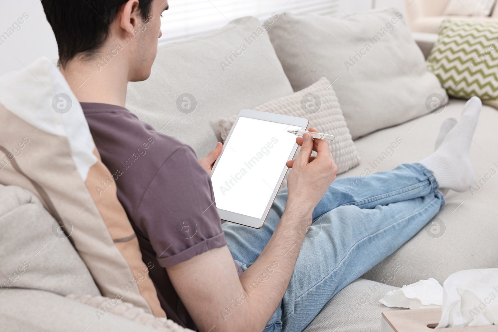 Photo of Sick man with thermometer having online consultation with doctor via tablet at home