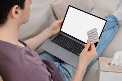 Photo of Sick man with pills having online consultation with doctor via laptop at home